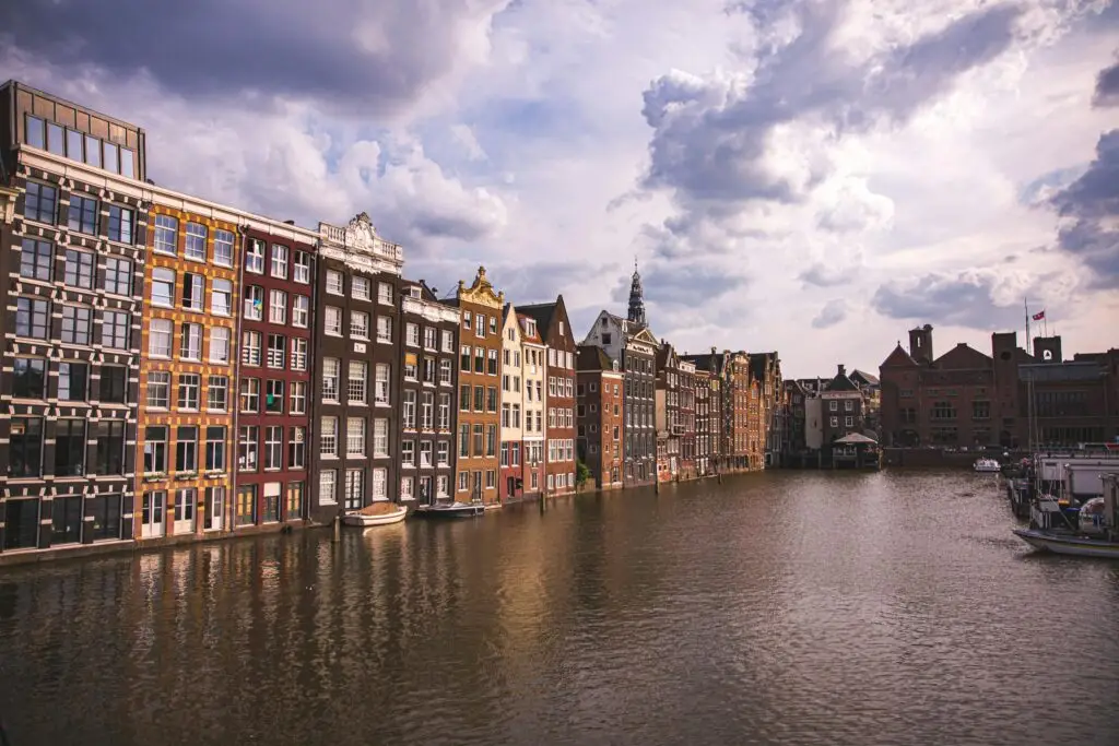 Amsterdam's iconic canals with colorful historic buildings under a cloudy sky.